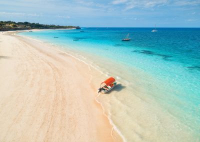 Aerial view of the fishing boat in clear blue water at sunset